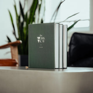 Green planner with silver accents on a surface with a blurred background
